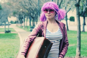 beautiful young woman with pink sunglasses and purple hair stand